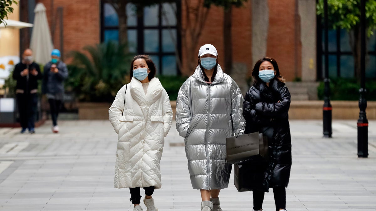 In this photo released by Xinhua News Agency, women wearing protective masks to prevent the new coronavirus outbreak walk on a re-opened commercial street in Wuhan in central China's Hubei province on Monday. (Shen Bohan/Xinhua via AP)