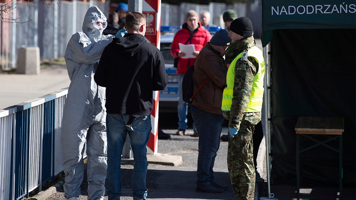 A man in a protective suit checking the body temperature of a man at a Polish border checkpoint on the Bridge of Friendship near Goerlitz, Germany, on Sunday. (Sebastian Kahnert/dpa via AP)