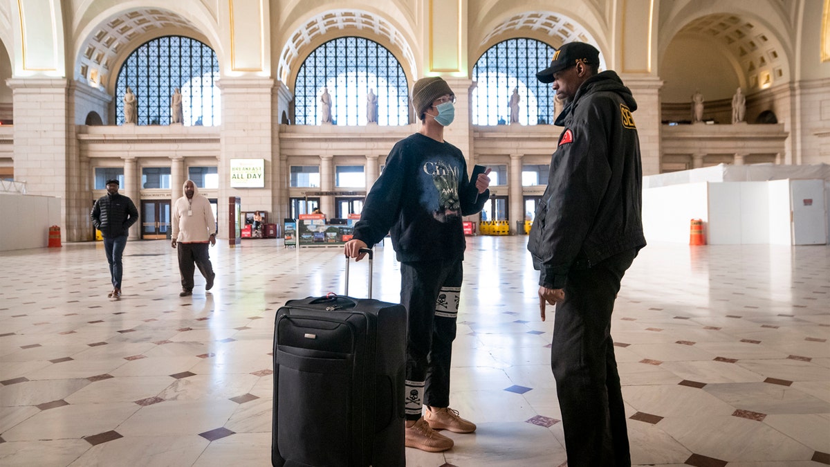 A traveler talks with a security officer at Washington Union Station, a major transportation hub in the nation's capital, Monday, March 16, 2020. The train station was nearly empty during morning rush hour as many government and private sector workers stay home during the coronavirus outbreak.