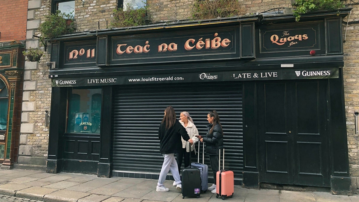 People standing outside The Quays Bar in Dublin, Ireland, on Sunday as pubs and clubs in Irish tourist hotspots closed with immediate effect amid coronavirus fears. (Aine McMahon/PA via AP)