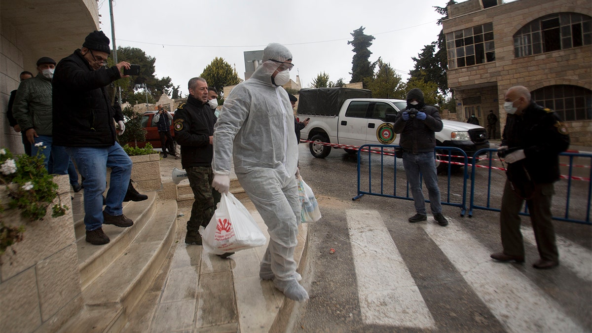 Palestinian policeman delivers supplies to the hotel staff which tested positive to coronavirus to a hotel in Bethlehem, West Bank, Friday. (AP Photo/Majdi Mohammed)