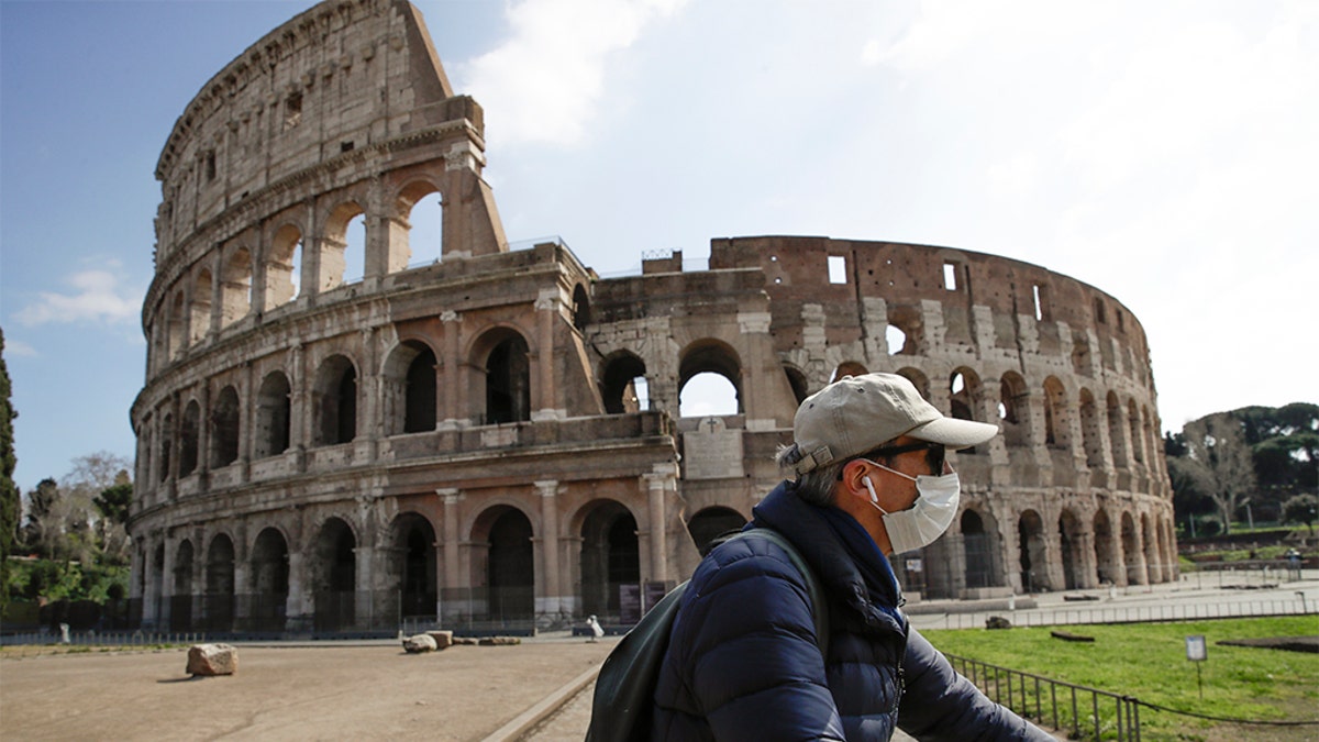 A man with a mask riding past the Colosseum in Rome on Sunday. (AP Photo/Alessandra Tarantino)