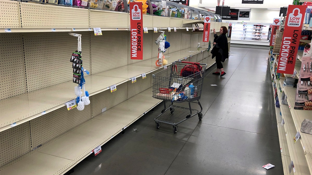 A woman shops among empty shelves at a Hy-Vee food store Friday, March 13, 2020, in Overland Park, Kan. (AP Photo/Charlie Riedel)