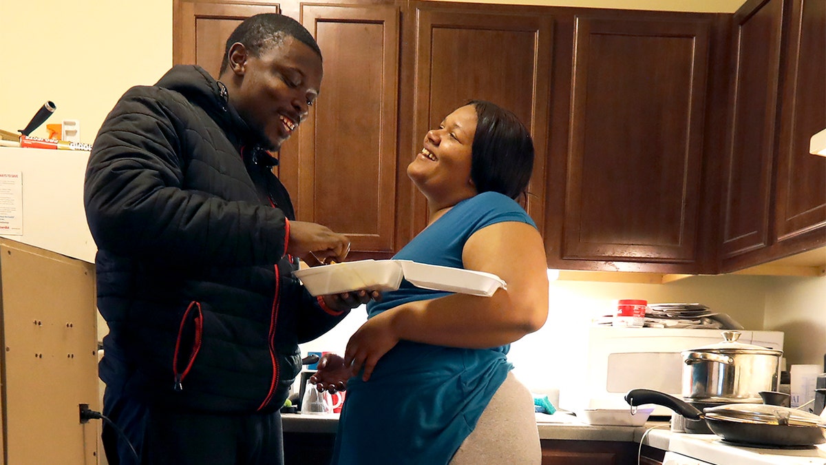 In this Thursday, Feb. 27, 2020, photo, Richard Butler and his fiance Amber laugh while they have breakfast in an apartment a friend is letting them live in on Chicago's Southside. (AP Photo/Charles Rex Arbogast)