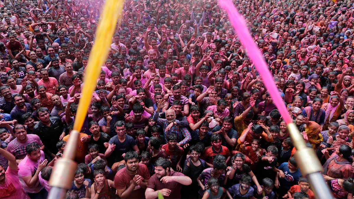 Indian Hindu devotees cheer as colored powder and water is sprayed on them by a Hindu priest during celebrations marking Holi at the Swaminarayan temple in Ahmedabad, India, Tuesday. Holi, the Hindu festival of colors, also marks the advent of spring. (AP Photo/Ajit Solanki)