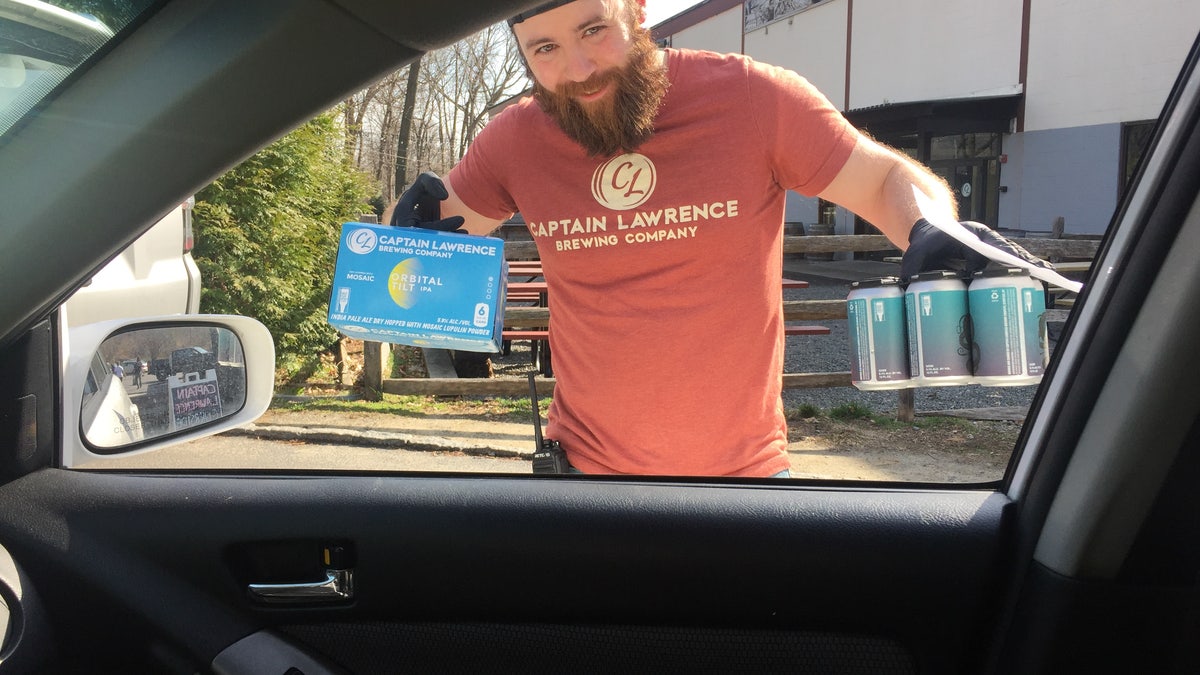 Rob, an employee of Captain Lawrence Brewing Co. in Elmsford, New York, makes a curbside no-contact drink delivery while wearing rubber gloves as part of the brewery's coronavirus precautions, and efforts to stay afloat during the statewide shutdown.Capt. Lawrence is using brewing equipment to make hundreds of gallons of chicken soup for a local food industry worker charity.?