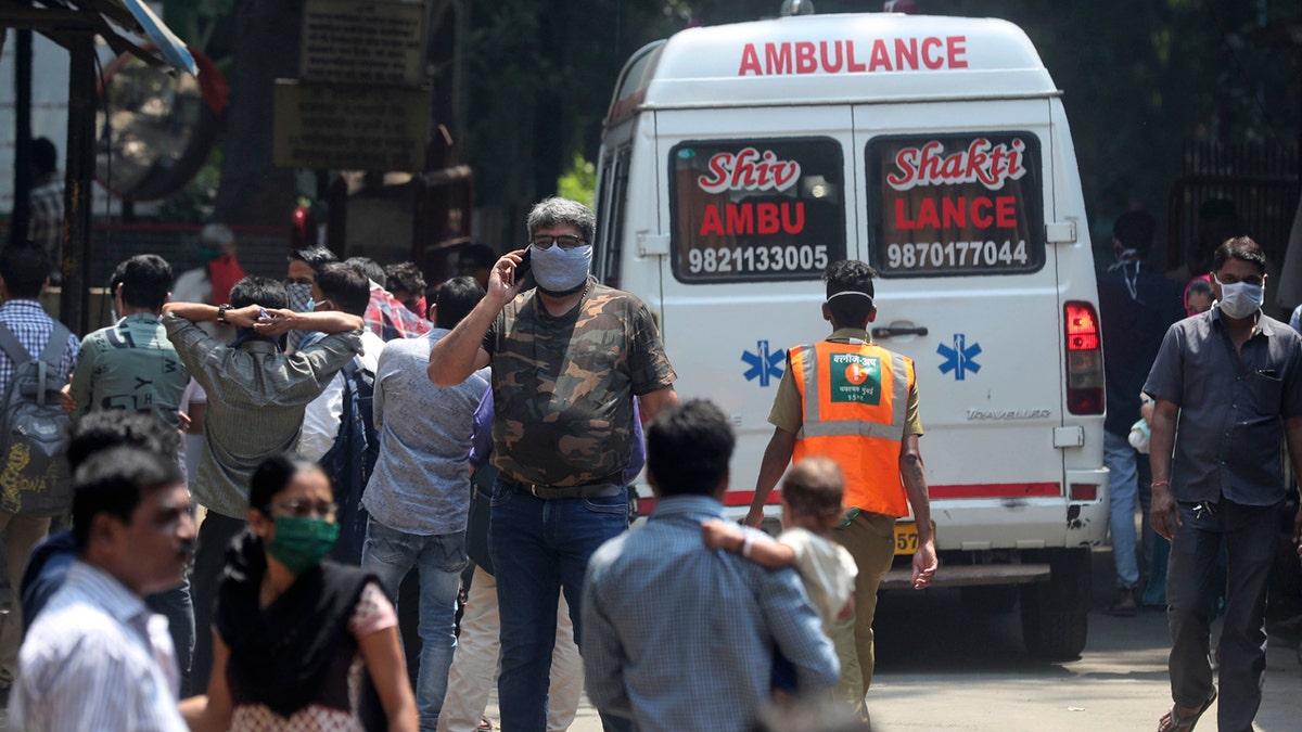 People wearing masks walk outside a special ward for possible COVID-19 patients at a hospital in Mumbai, India, Tuesday, March 17, 2020.