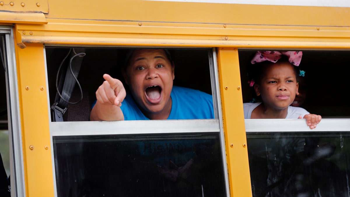 A congregant in a church bus yells out to news media as they leave services at the Life Tabernacle Church in Central, La., Sunday, March 29, 2020. Pastor Tony Spell has defied a shelter-in-place order by Louisiana Gov. John Bel Edwards, due to the new coronavirus pandemic, and continues to hold church services with hundreds of congregants. (AP Photo/Gerald Herbert)