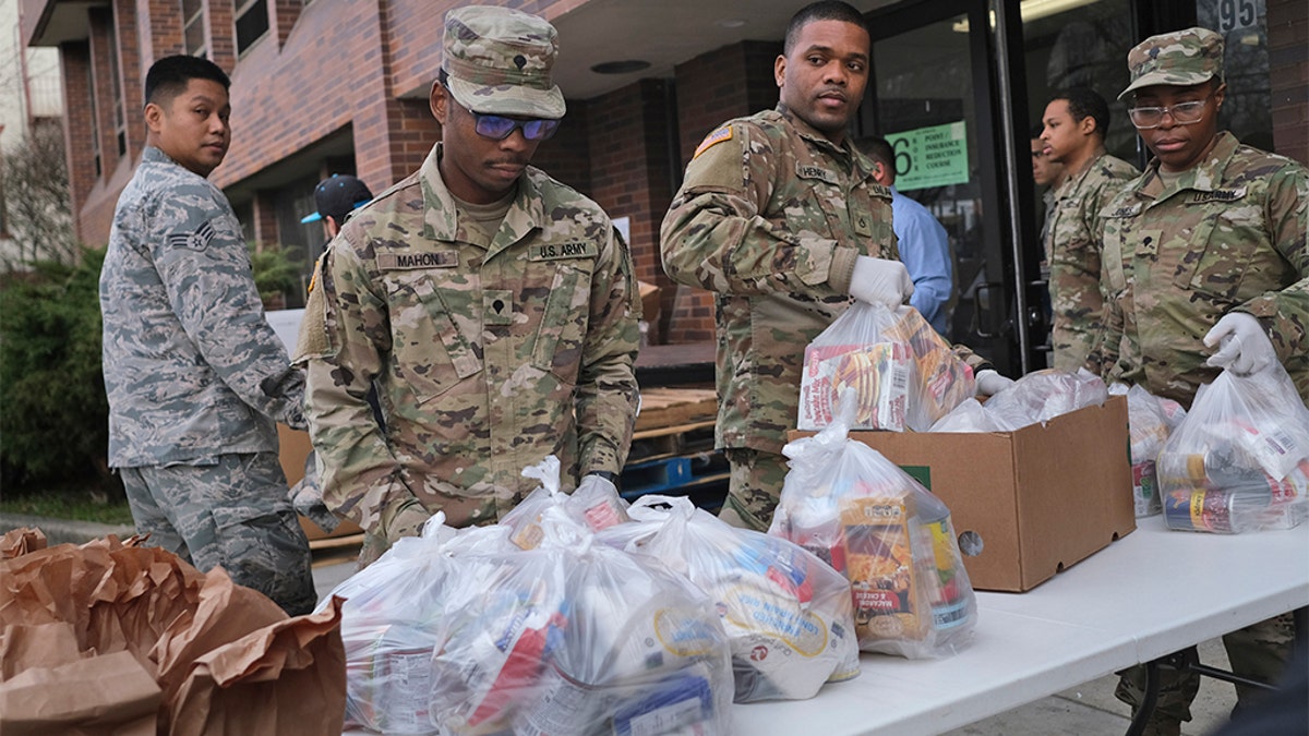 Members of the New York National Guard help to organize and distribute food to families on free or reduced school lunch programs in New Rochelle, N.Y., Thursday, March 12, 2020. State officials have set up a “containment area” in the New York City suburb, where schools and houses of worship are closed within a 1-mile radius of a point near a synagogue where an infected person with coronavirus had attended events. State officials stress it is not a lockdown. The vast majority of people recover from the new coronavirus. According to the World Health Organization, most people recover in about two to six weeks, depending on the severity of the illness. (AP Photo/Seth Wenig)