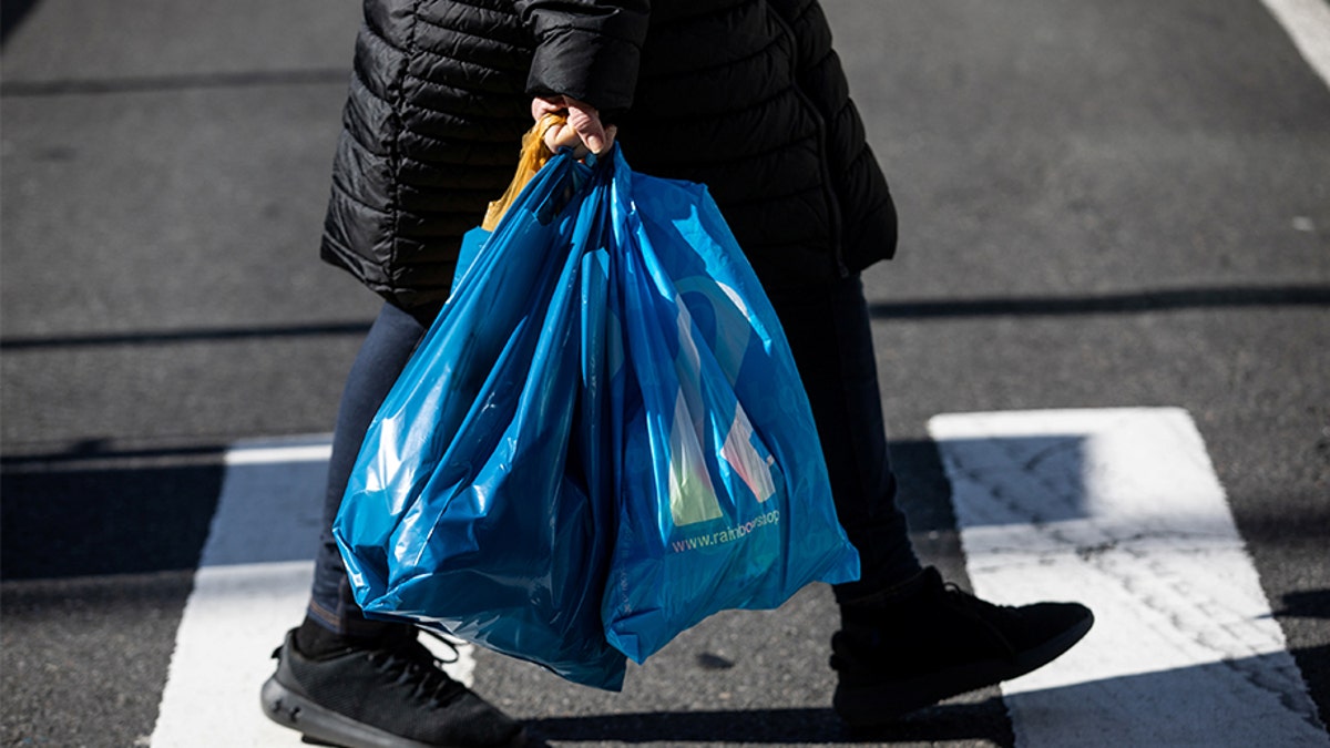 Photo shows person holding plastic bags after shopping