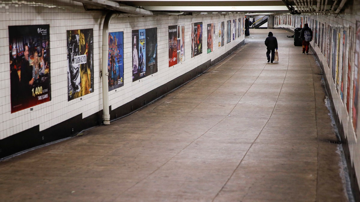 A subway customer walks through an empty underground passage in the Brooklyn borough of New York, Monday, March 16, 2020.