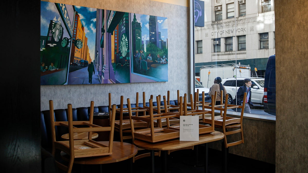 Chairs are stacked in a Starbucks coffee shop that remained open for customers purchasing for take-away, Monday, March 16, 2020, in New York.