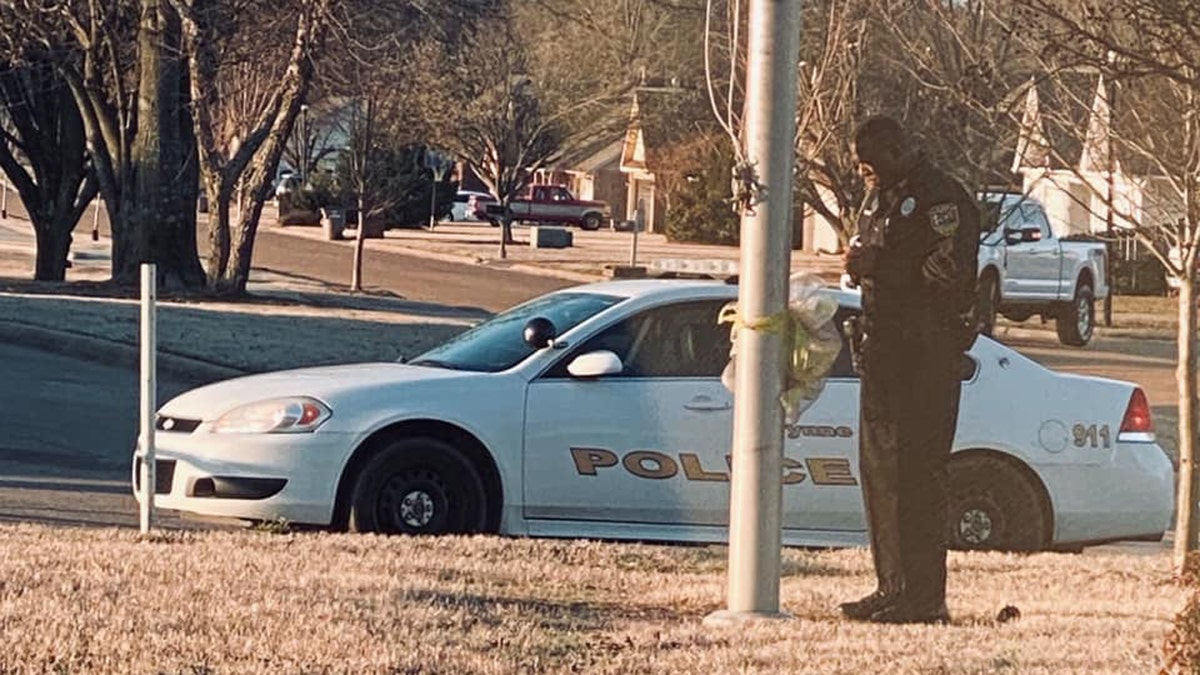 Officer DeAndra Warren stands at the flag pole, praying for students. The photo shared by his 21-year-old daughter, De'Andria, went viral online.