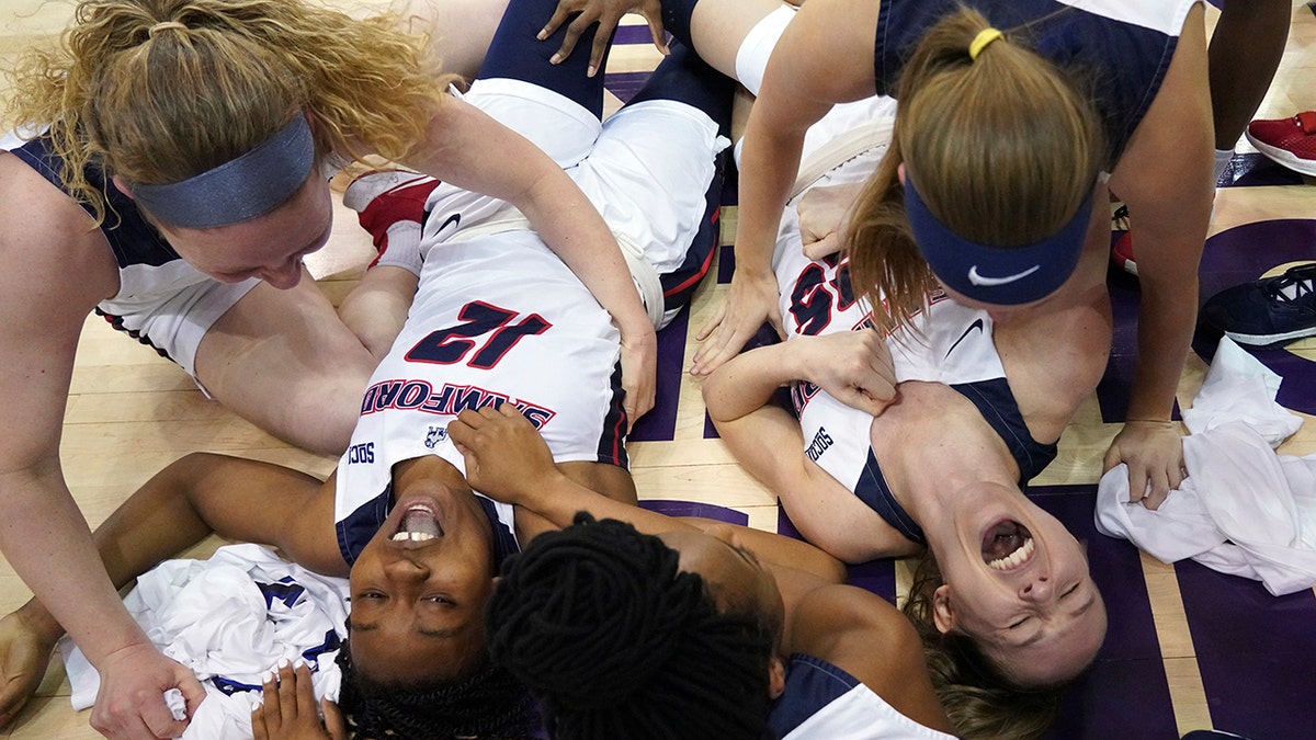 Samford guards Charity Brown (12) and Sarah Myers (25) fall to the floor to celebrate with teammates after their win over UNC Greensboro for the NCAA women's college basketball Southern Conference championship tournament, Sunday, March 8, 2020, in Asheville, N.C. (AP Photo/Kathy Kmonicek)