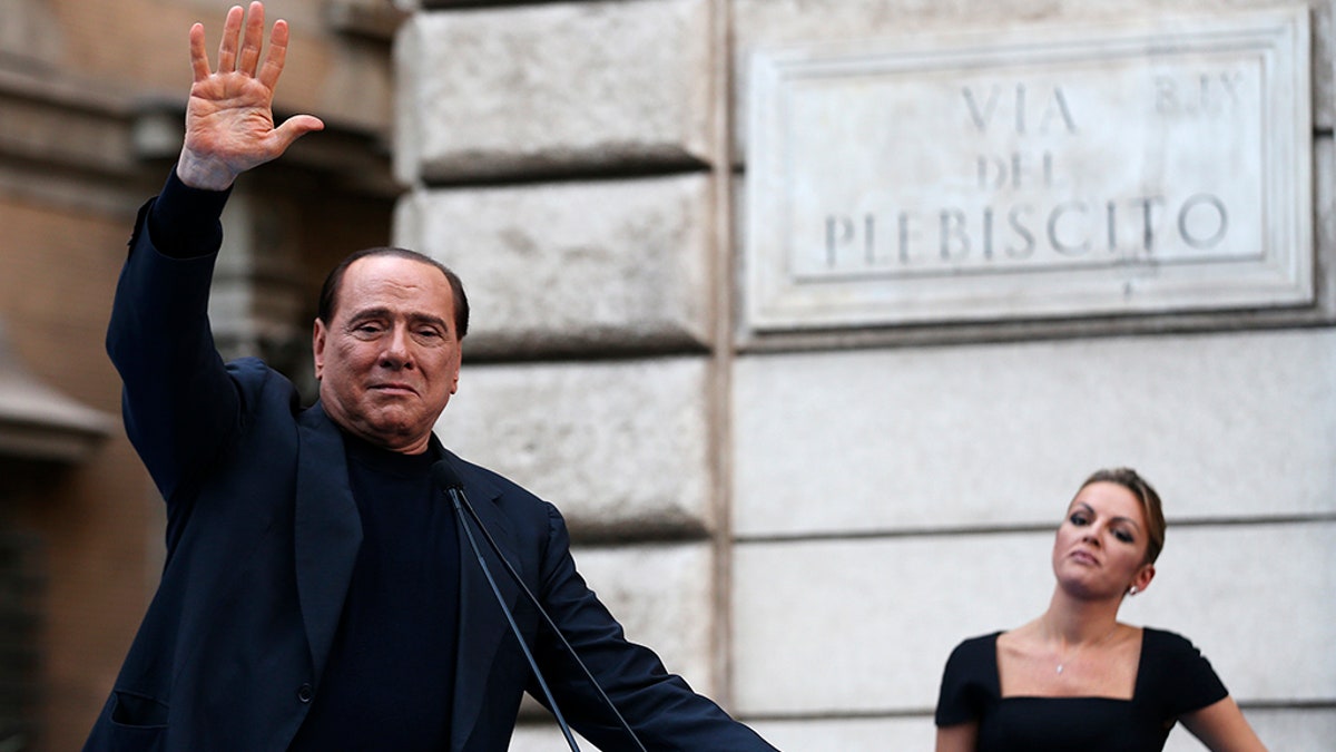 Former Italian Prime Minister Silvio Berlusconi waves to supporters as his girlfriend Francesca Pascale looks on during a rally to protest his tax fraud conviction, outside his palace in central Rome August 4, 2013. Tensions in Italy's squabbling coalition heightened ahead of a rally by supporters of Silvio Berlusconi in Rome on Sunday in protest at a tax fraud conviction that threatens his future in politics and the fragile government. REUTERS/Alessandro Bianchi (ITALY - Tags: POLITICS CIVIL UNREST) - GM1E98503SQ01