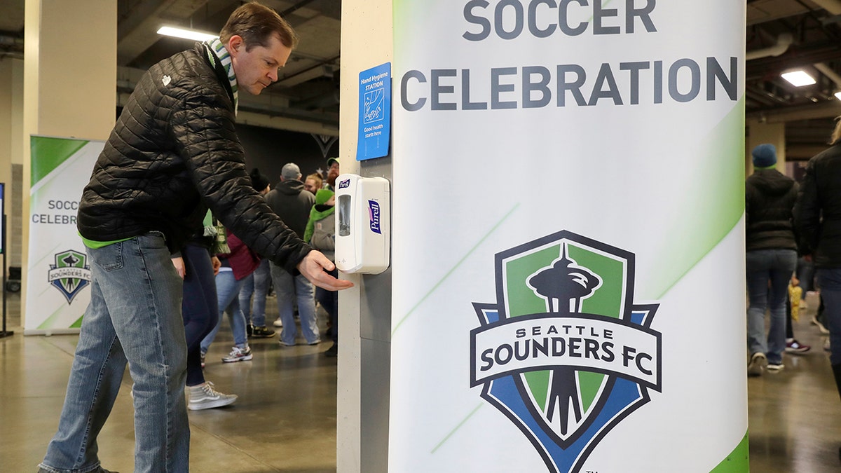 A man makes use of a hand-sanitizing station at CenturyLink Field prior to an MLS soccer match between the Seattle Sounders and the Chicago Fire, Sunday, March 1, 2020, in Seattle. Major North American professional sports leagues are talking to health officials and informing teams about the coronavirus outbreak. (AP Photo/Ted S. Warren)