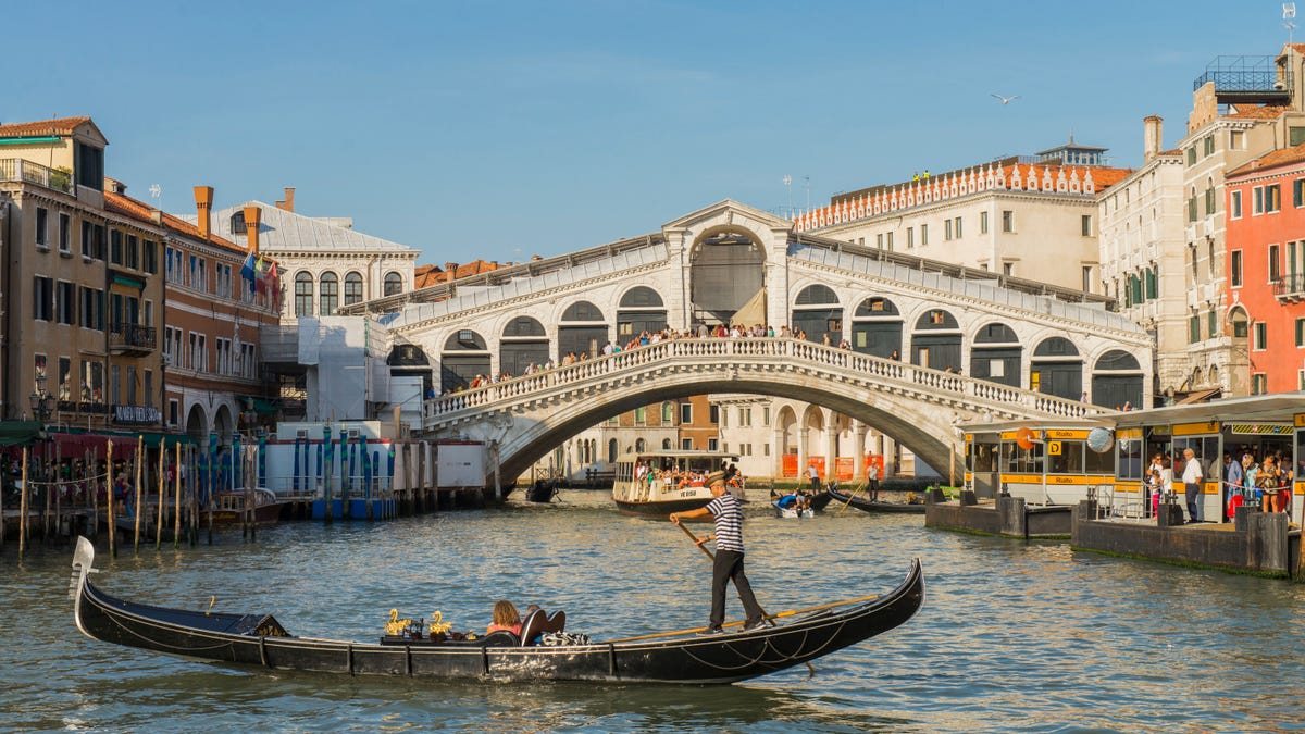 Gondola tour with tourist near the Rialto Bridge at Venice, Italy.