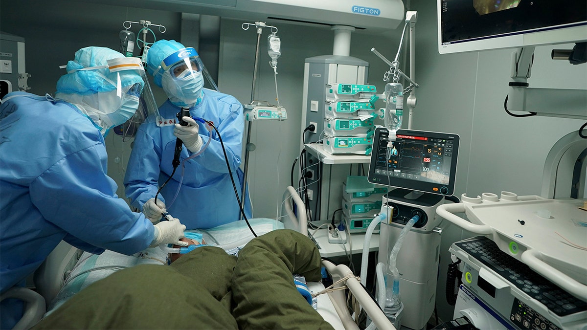 In this March 17, 2020 photo released by China's Xinhua News Agency, medical workers use a bronchoscope to treat a coronavirus patient at the Huoshenshan field hospital in Wuhan in central China's Hubei Province. Last month, Wuhan was overwhelmed with thousands of new cases of coronavirus each day. 