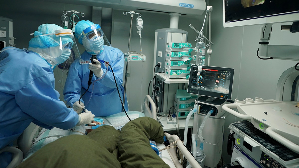 In this March 17, 2020 photo released by China's Xinhua News Agency, medical workers use a bronchoscope to treat a coronavirus patient at the Huoshenshan field hospital in Wuhan in central China's Hubei Province. Last month, Wuhan was overwhelmed with thousands of new cases of coronavirus each day.