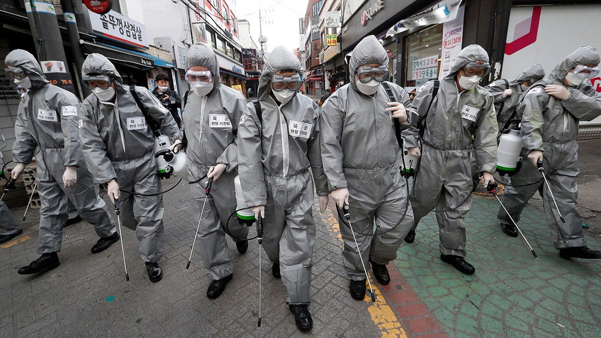 Army soldiers wearing protective suits spray disinfectant as a precaution against the new coronavirus at a shopping street in Seoul, South Korea, Wednesday, March 4, 2020. (AP Photo/Ahn Young-joon)