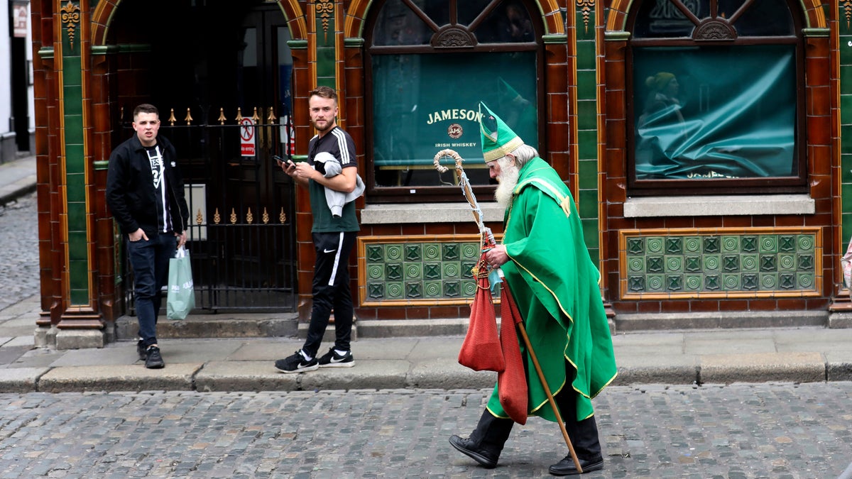 A man dressed as St Patrick walks past a closed bar in Dublin city center, Monday, March, 16, 2020.