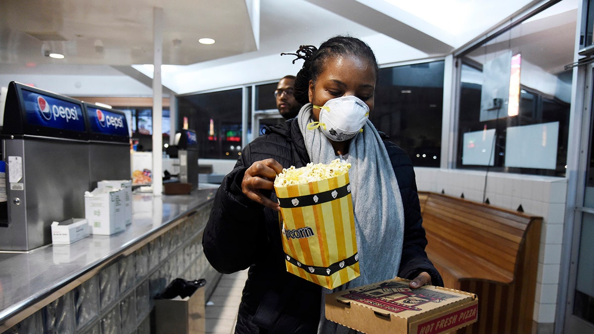 Andrea Wyatt of Inglewood, Calif., wears a mask as she collects her concessions at the Paramount Drive-In Theatres, Thursday, March 19 in Paramount, Calif. The drive-in theater, long a dwindling nostalgia act in a multiplex world, is experiencing a momentary return to prominence. With nearly all of the nation’s movie theaters shuttered due to the pandemic, some drive-in owners think they’re in a unique position to give moviegoers a chance to do something out of the house but stay within prudent distance from one another.