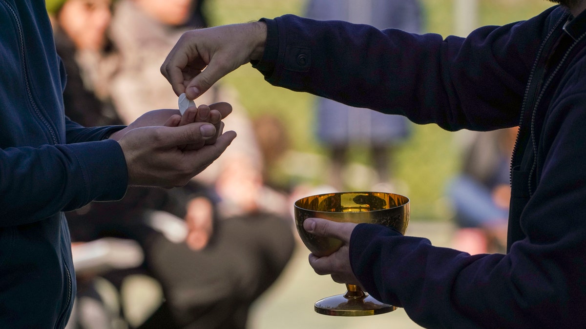 A priest offers a faithful the communion during a Sunday Mass outdoors mass celebrated in their parish soccer field, on the second Sunday of Lent, the first one after Italy's government's prevention measures on public gatherings, in Rome, Sunday, March 8, 2020. (AP Photo/Andrew Medichini)