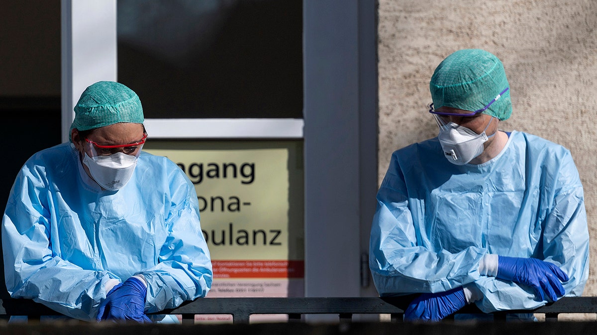 Employees of the Corona Outpatient Clinic at the University Hospital stand in protective clothing and breathing masks in front of the entrance in Dresden, Germany, on Wedneday. (Robert Michael/dpa via AP)