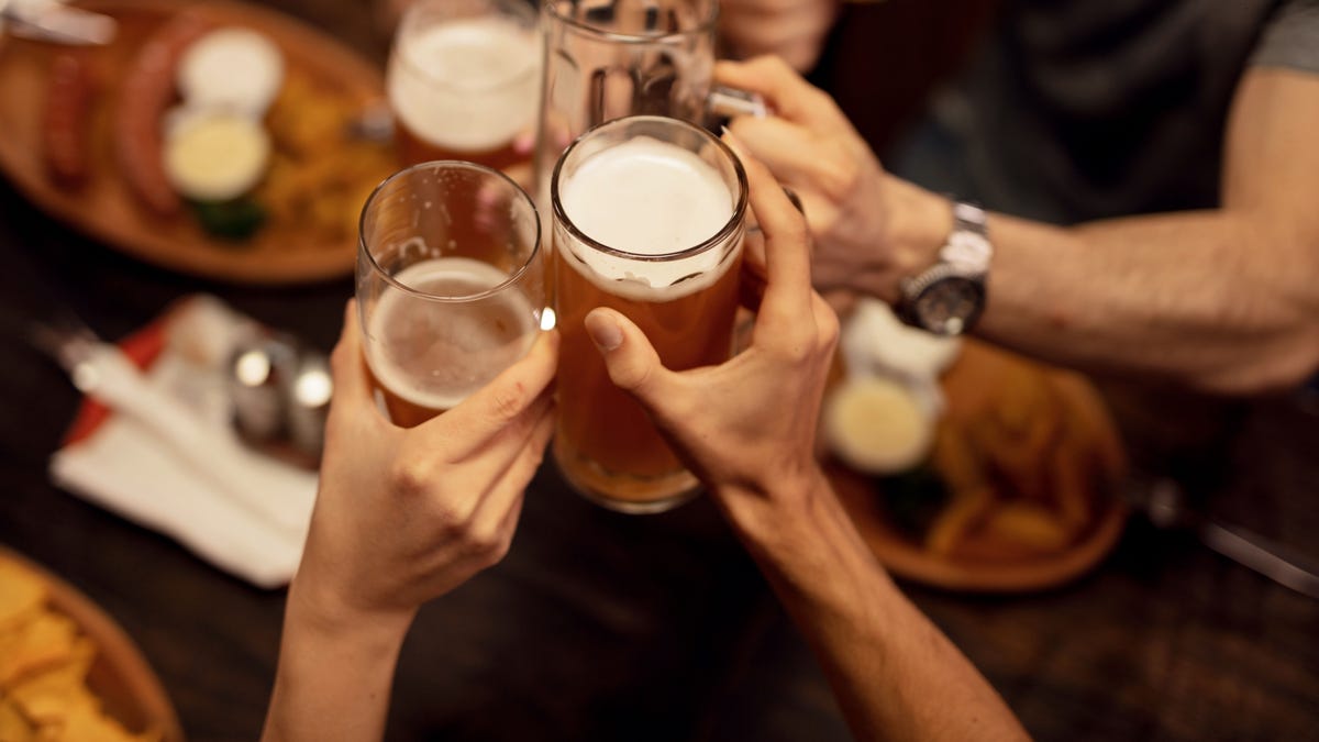 Close up of friends toasting with beer and having fun in a pub.