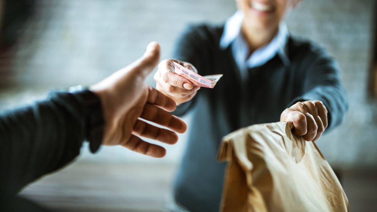 Close up of a woman giving money to delivery person.