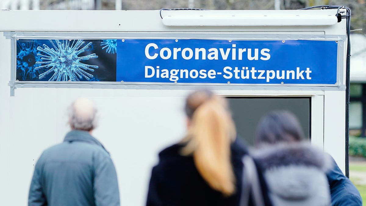 People stand in front of containers with a banner reading "Coronavirus Diagnosis Base" on the grounds of the University Hospital in Mannheim, Germany, on Wednesday. (Uwe Anspach/dpa via AP)
