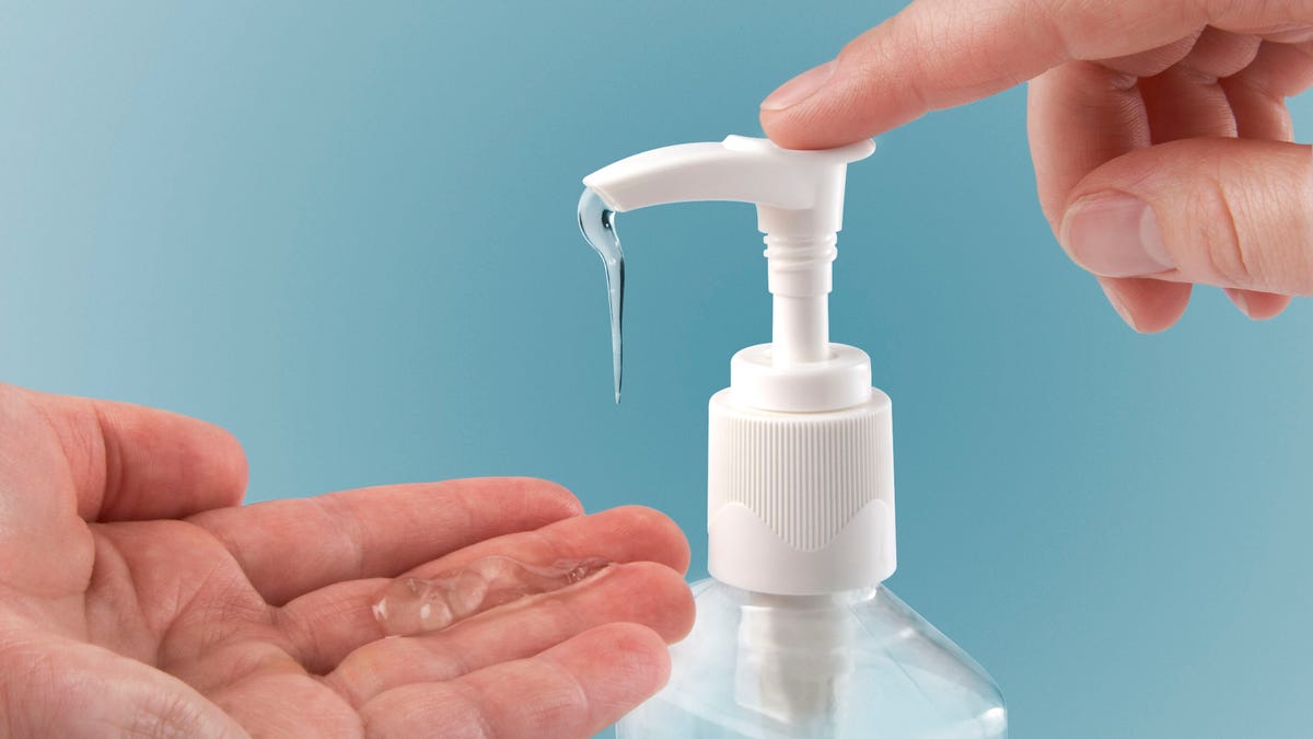 Photograph of a finger pumping sanitizer onto hand