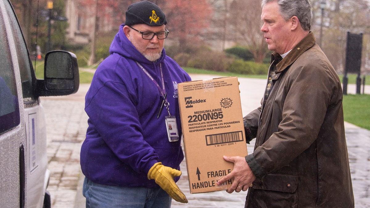 The Very Rev. Randolph Marshall Hollerith, dean of Washington National Cathedral, on the right, helps load boxes of masks to be taken to local hospitals.