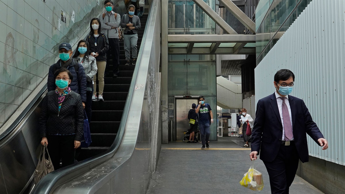 People wearing face masks walk at a downtown street in Hong Kong Monday, March 16, 2020.