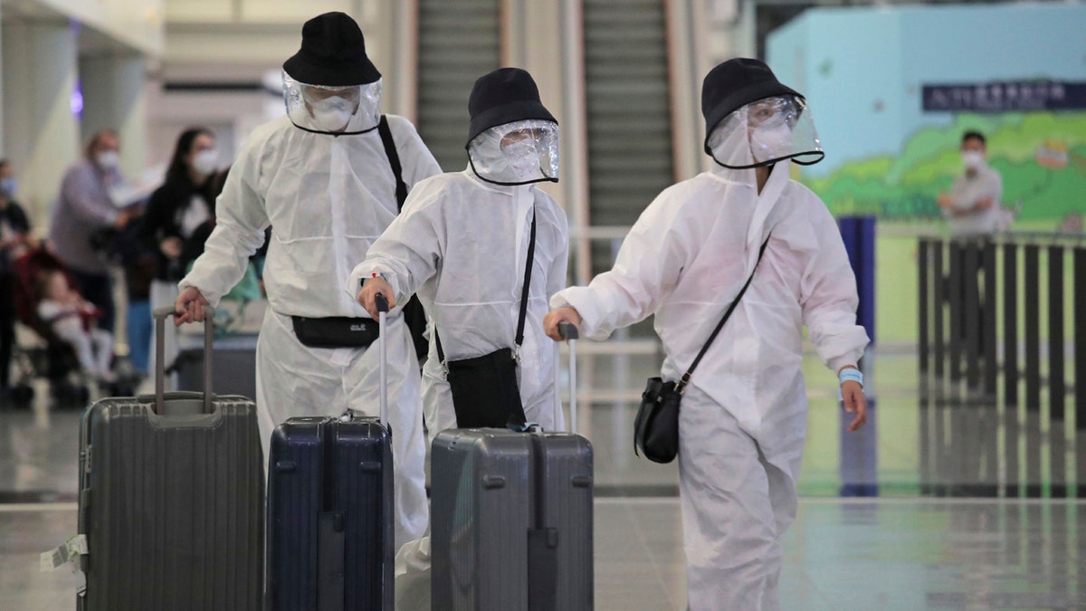 Passengers wear protective suits and face masks as they arrive at the Hong Kong airport, Monday, March 23, 2020.