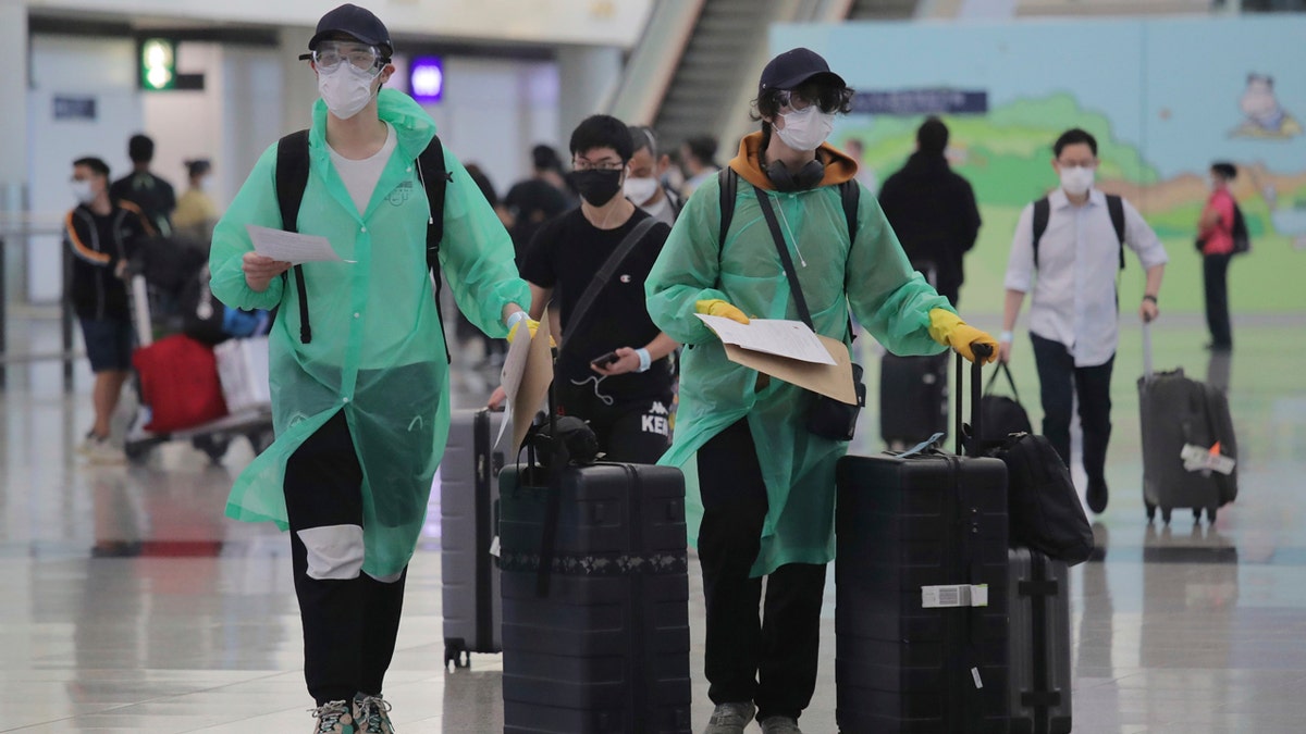 Passengers wear protective suits and face masks to protect themselves from possibly contracting the coronavirus after arriving at the Hong Kong airport, Monday, March 23, 2020.