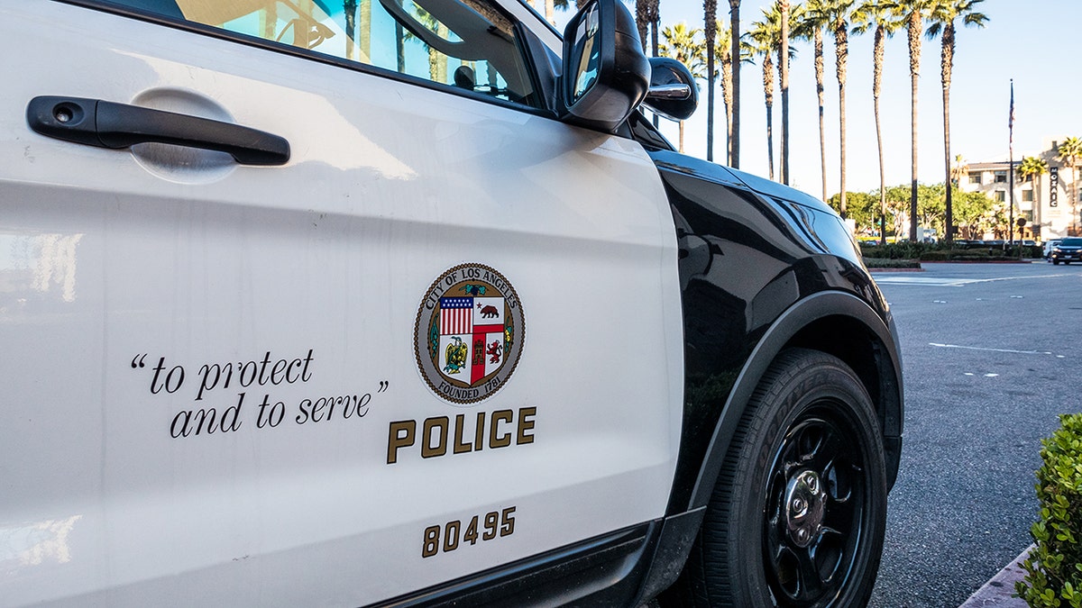 Los Angeles, USA - Close-up on the insignia and slogan of a LAPD vehicle, with the reflection of Union Stations tower visible in the cars window.