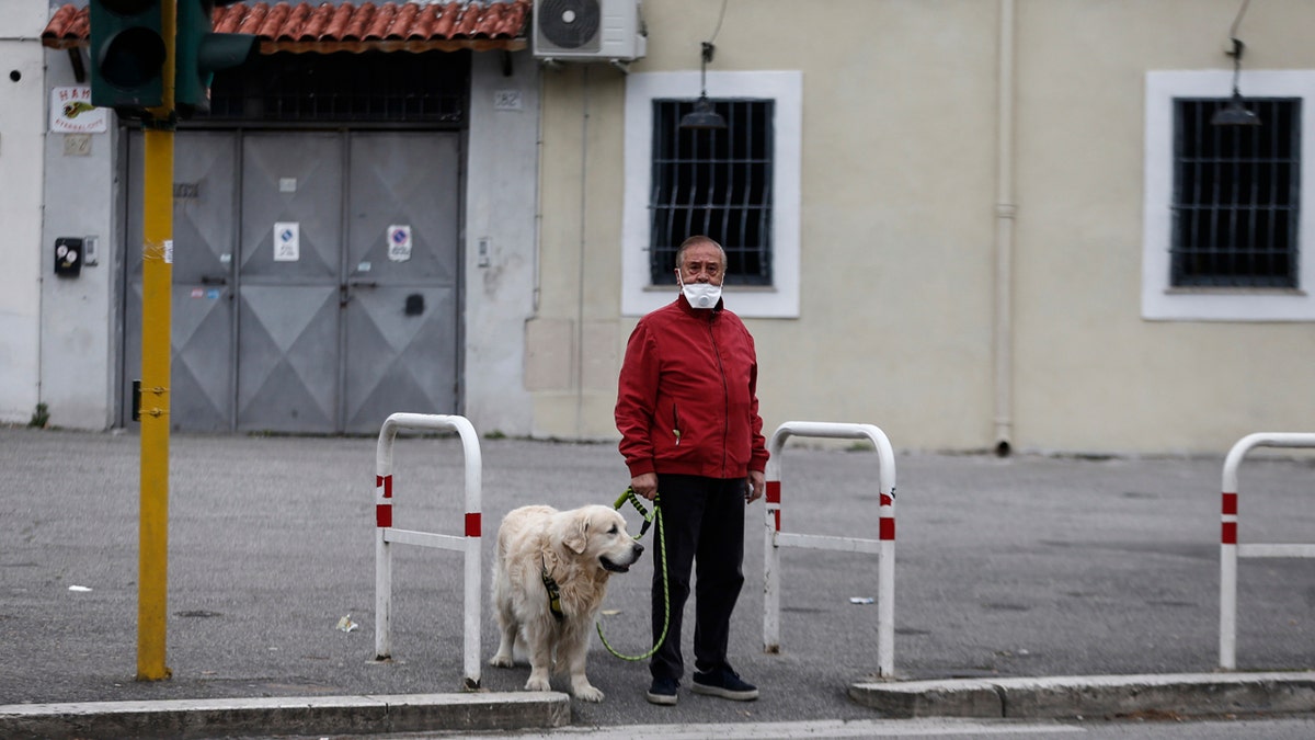 A man strolls with his dog in Rome Friday, March 13, 2020. A sweeping lockdown is in place in Italy to try to slow down the spread of coronavirus epidemic.