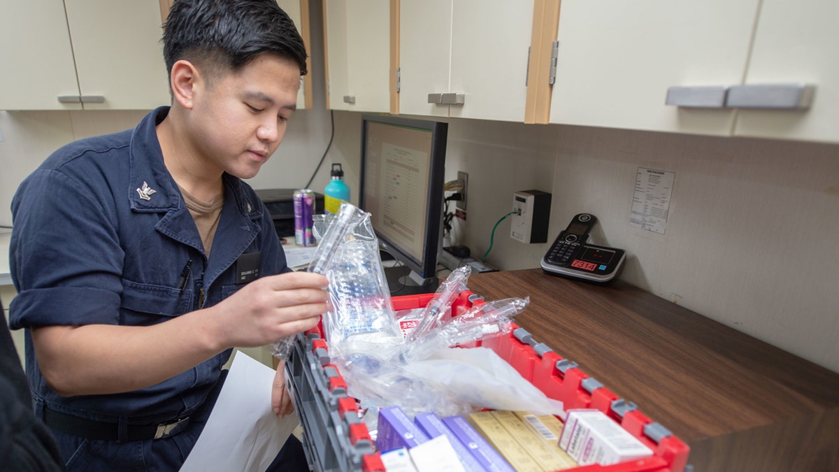 Hospital Corpsman 2nd Class Benjamin Ong, from Bremerton, Wash., assembles emergency medicine carts aboard the hospital ship USNS Mercy on Wedneday. Mercy deployed in support of the nation's COVID-19 response efforts.
