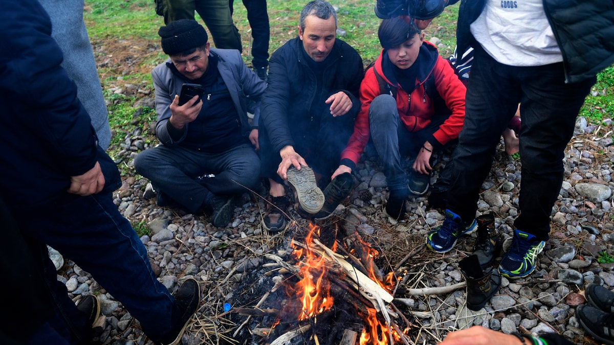 Migrants try to warm themselves around bonfire at the village of Skala Sikaminias, on the Greek island of Lesbos, after crossing on a dinghy the Aegean sea from Turkey, Sunday, March 1, 2020.