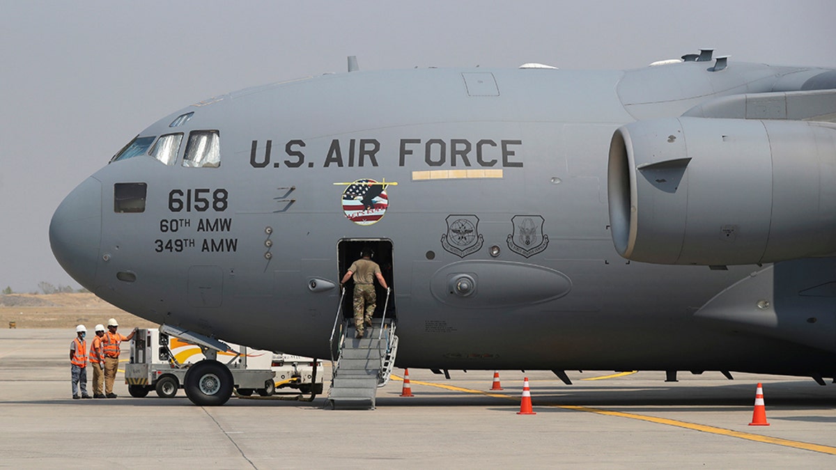 A staff gets on U.S. Air Force plane at Mandalay international airport during a repatriation ceremony Thursday, March 12, 2020, in Mandalay, central Myanmar. (AP Photo/Thein Zaw)