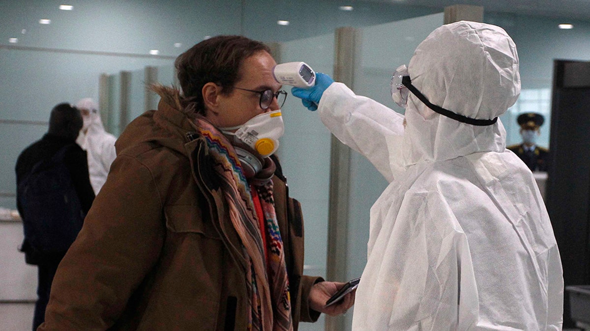In this March 9 photo, a passenger wearing a mask as a precaution against a new coronavirus has his temperature checked before boarding a flight to Vladivostok, Russia, at the Pyongyang International Airport in Pyongyang, North Korea.