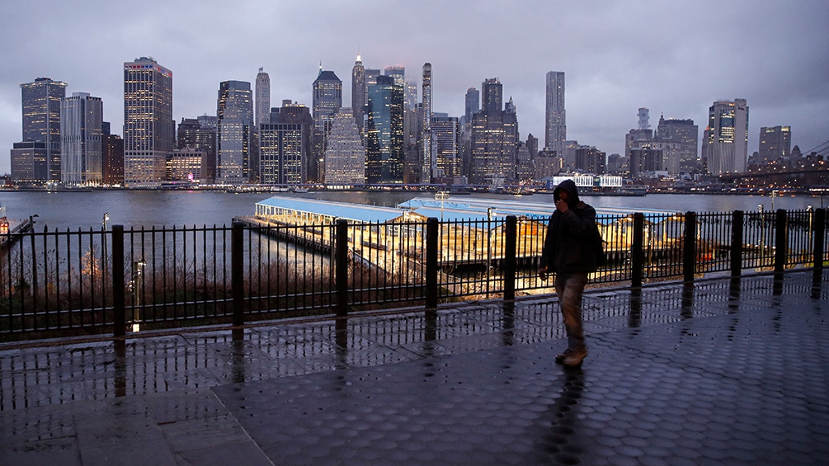 A person walks on an empty sidewalk across from the Manhattan skyline on Tuesday. (AP Photo/John Minchillo)