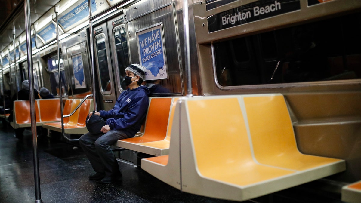 A commuter wears a face mask while riding the a nearly empty subway car into Brooklyn, Thursday, March 12, 2020, in New York. (AP Photo/John Minchillo)