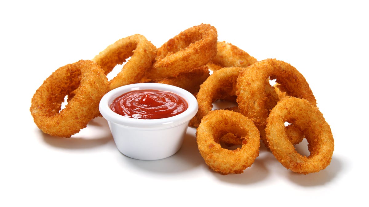 Cooked onion rings with dipping sauce in a white cup