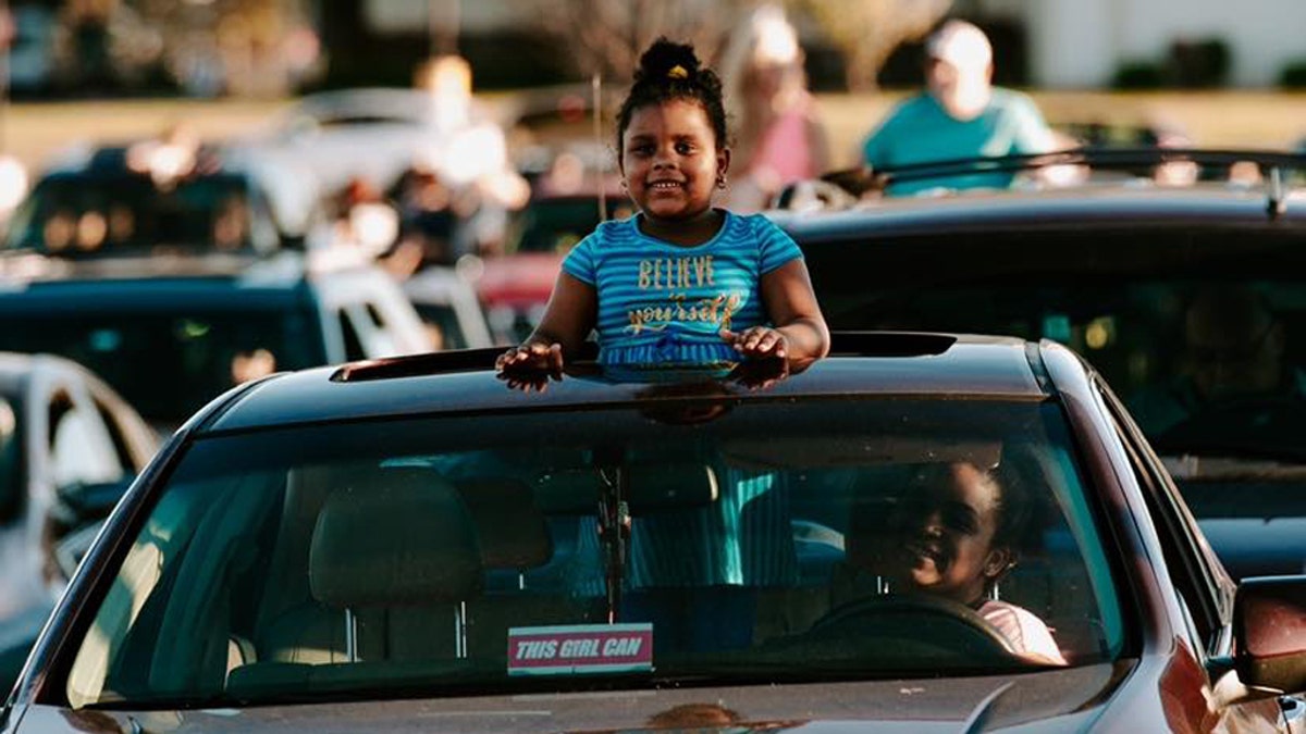 A young girl pops her head through the sunroof while attending a drive-in service at Victory Church in Tulsa, Oklahoma.