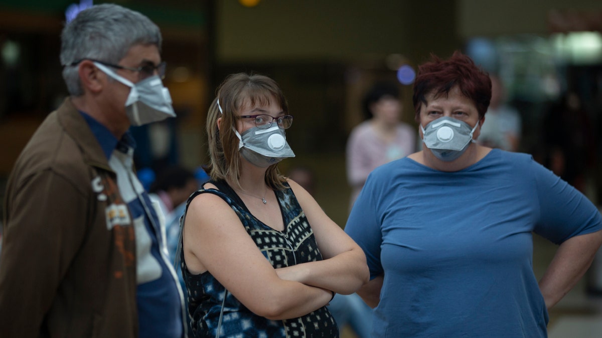 People wearing masks wait for passengers at Johannesburg's O.R. Tambo International Airport, Monday, March 16, 2020 a day after President Cyril Ramaphosa declared a national state of disaster.