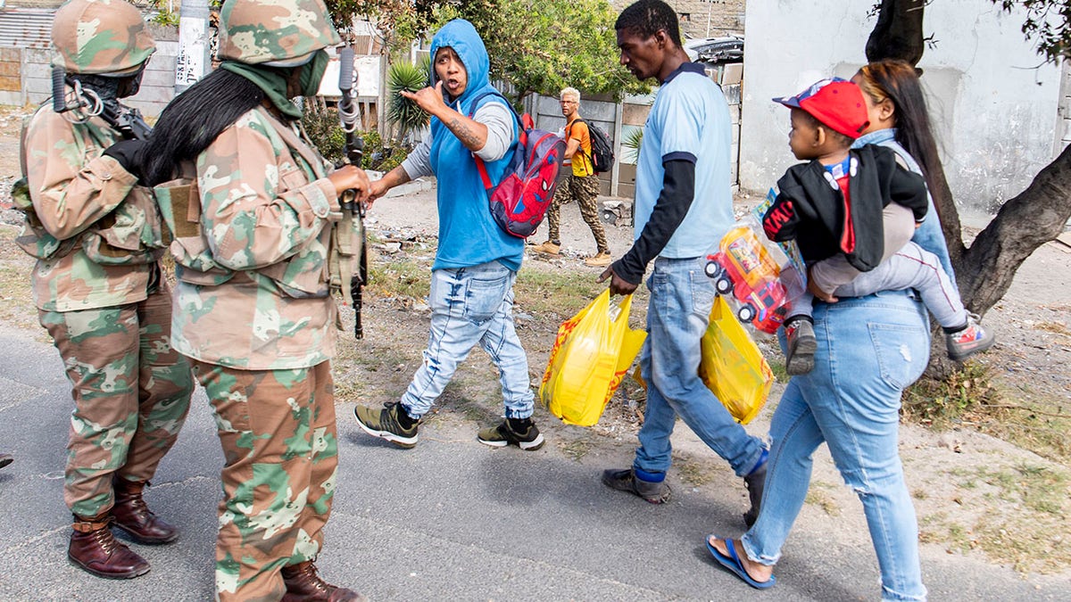 Soldiers interact with resident while on patrol in Mannenburg, Cape Town, South Africa on Saturday. (AP Photo)