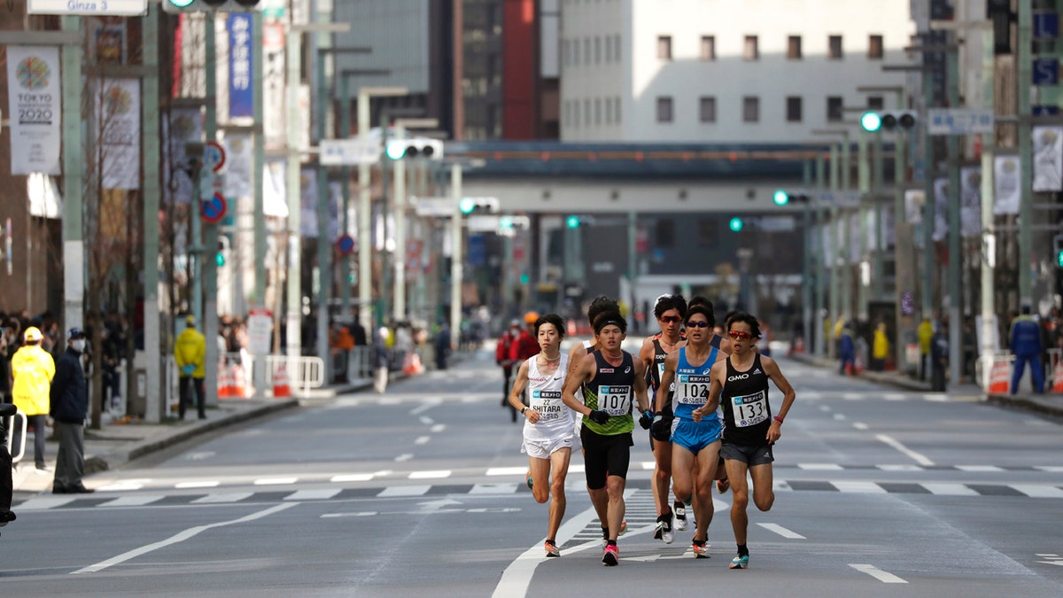 Runners race through the commercial district with less spectators at the Tokyo Marathon in Tokyo, Sunday, March 1, 2020.