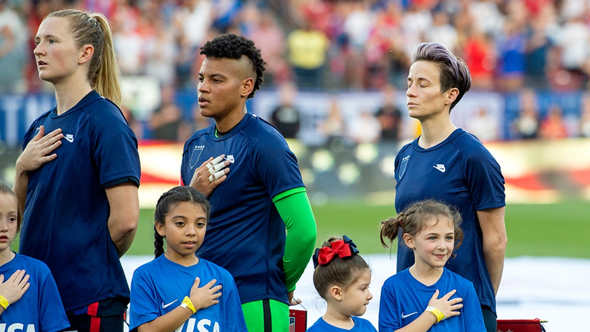 U.S. midfielder Samantha Mewis (3), goalkeeper Adrianna Franch, center, and forward Megan Rapinoe, right, stand with their jerseys turned inside out during the playing of the national anthem before a SheBelieves Cup women's soccer match against Japan, March 11, 2020 at Toyota Stadium in Frisco, Texas. (Associated Press)